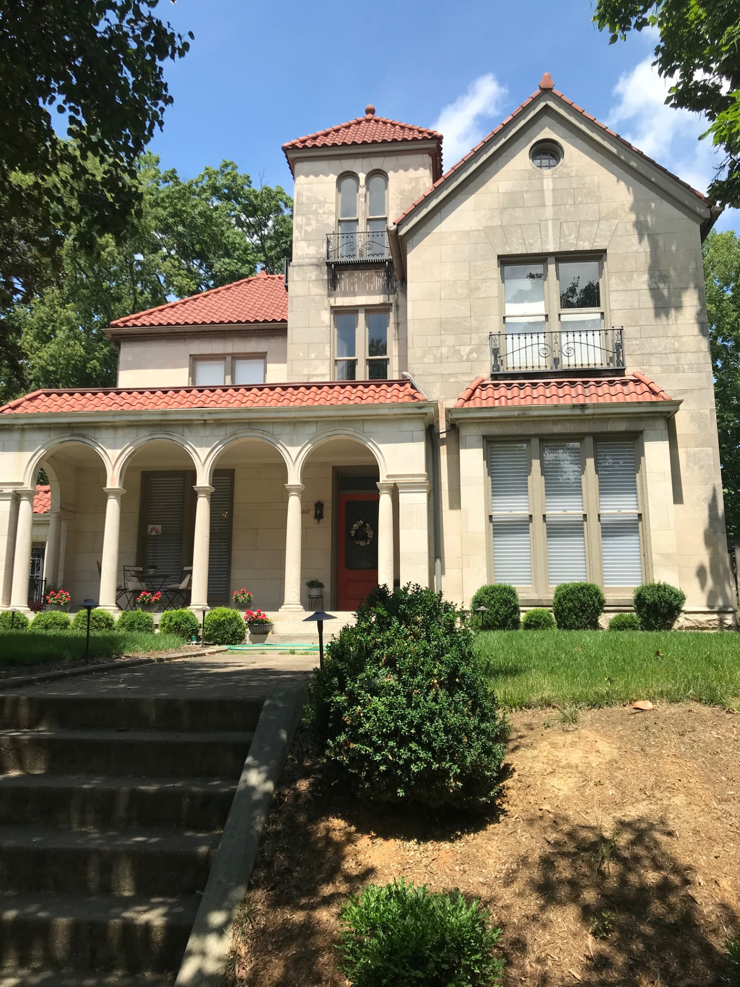 Historic limestone home with clay tile roof, arched colonnade porch and wrought iron balconies