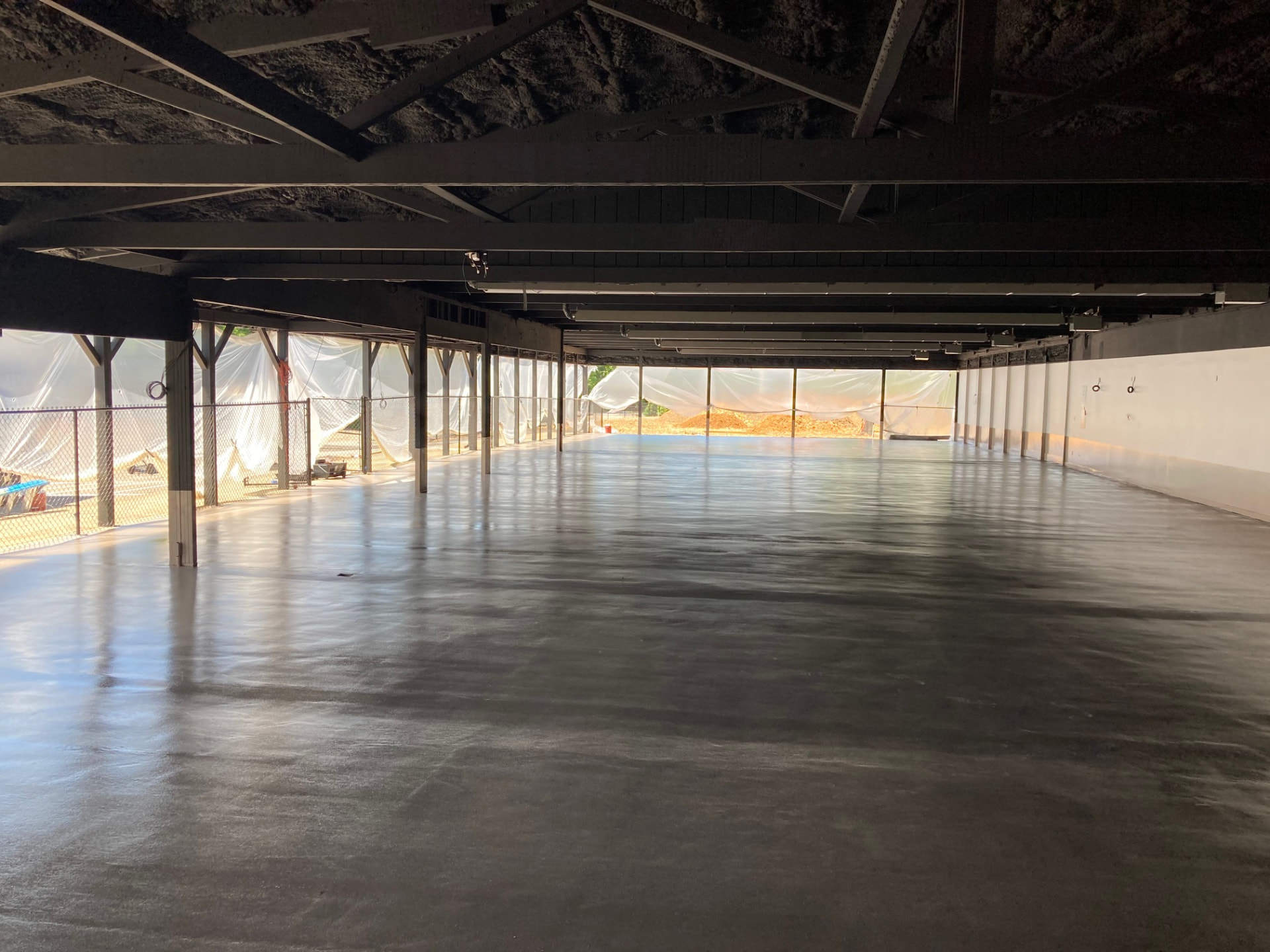 Large open interior with a freshly finished concrete slab and painted steel structure overhead