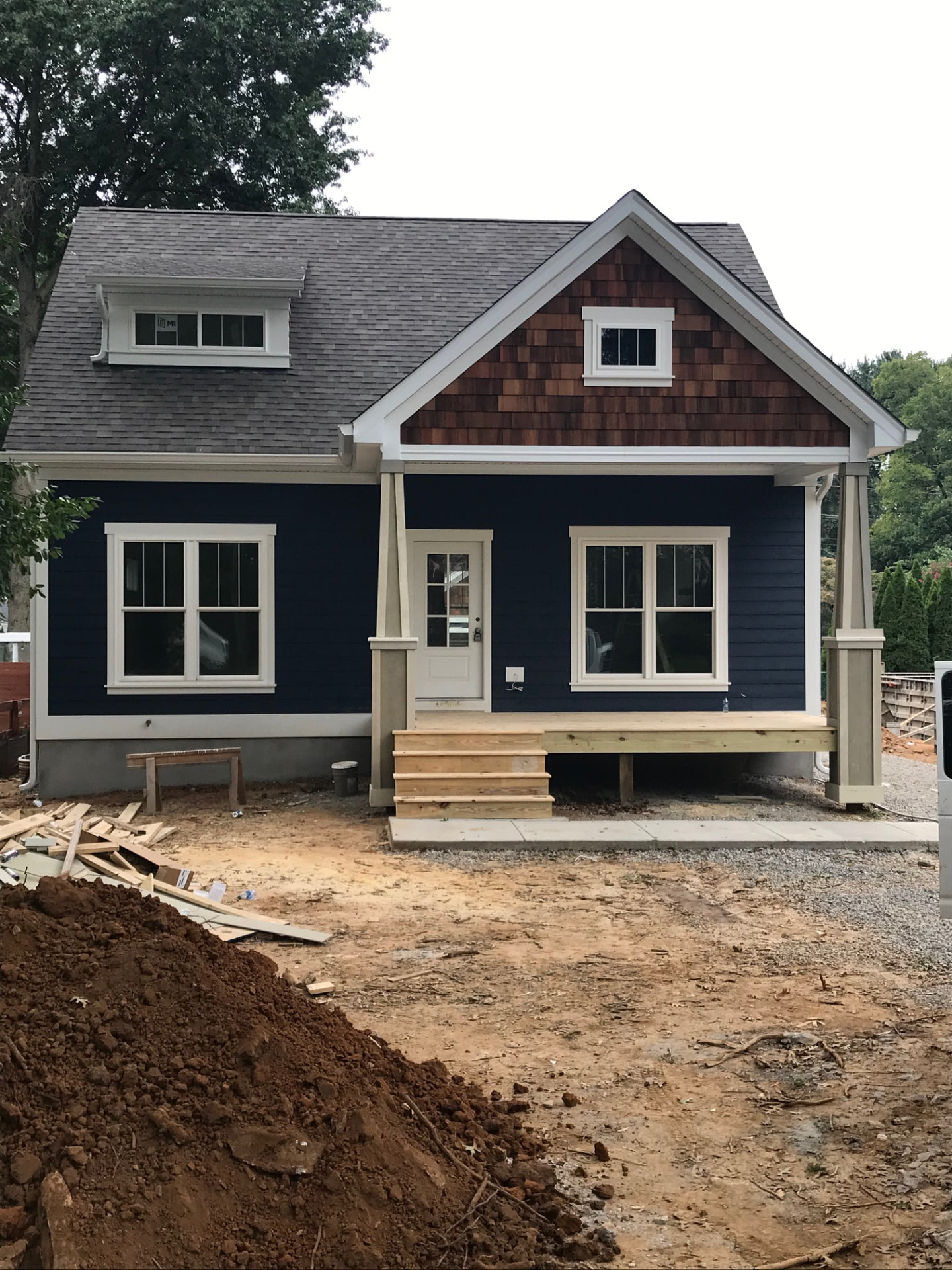 Newly built craftsman home with navy siding, cedar shake gable and a covered front porch