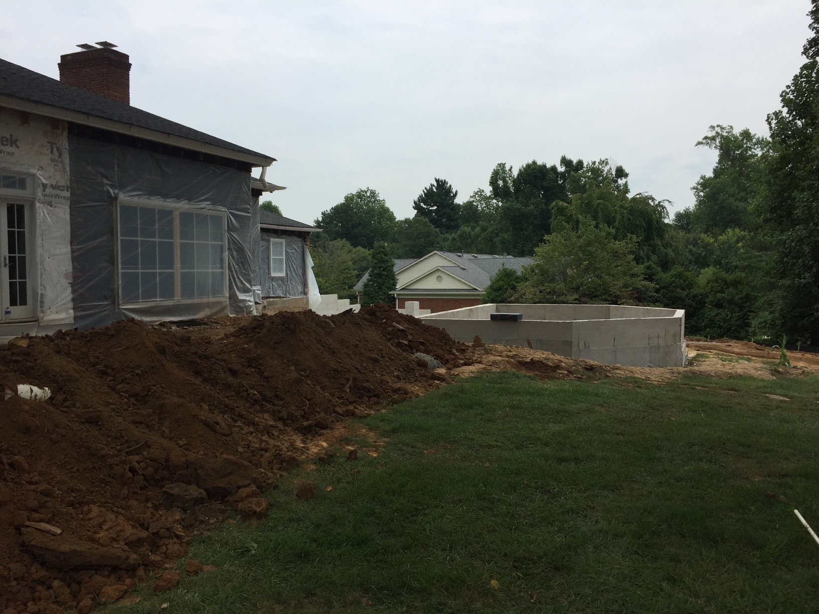 Poured block foundation for a home addition beside an existing house wrapped in house wrap