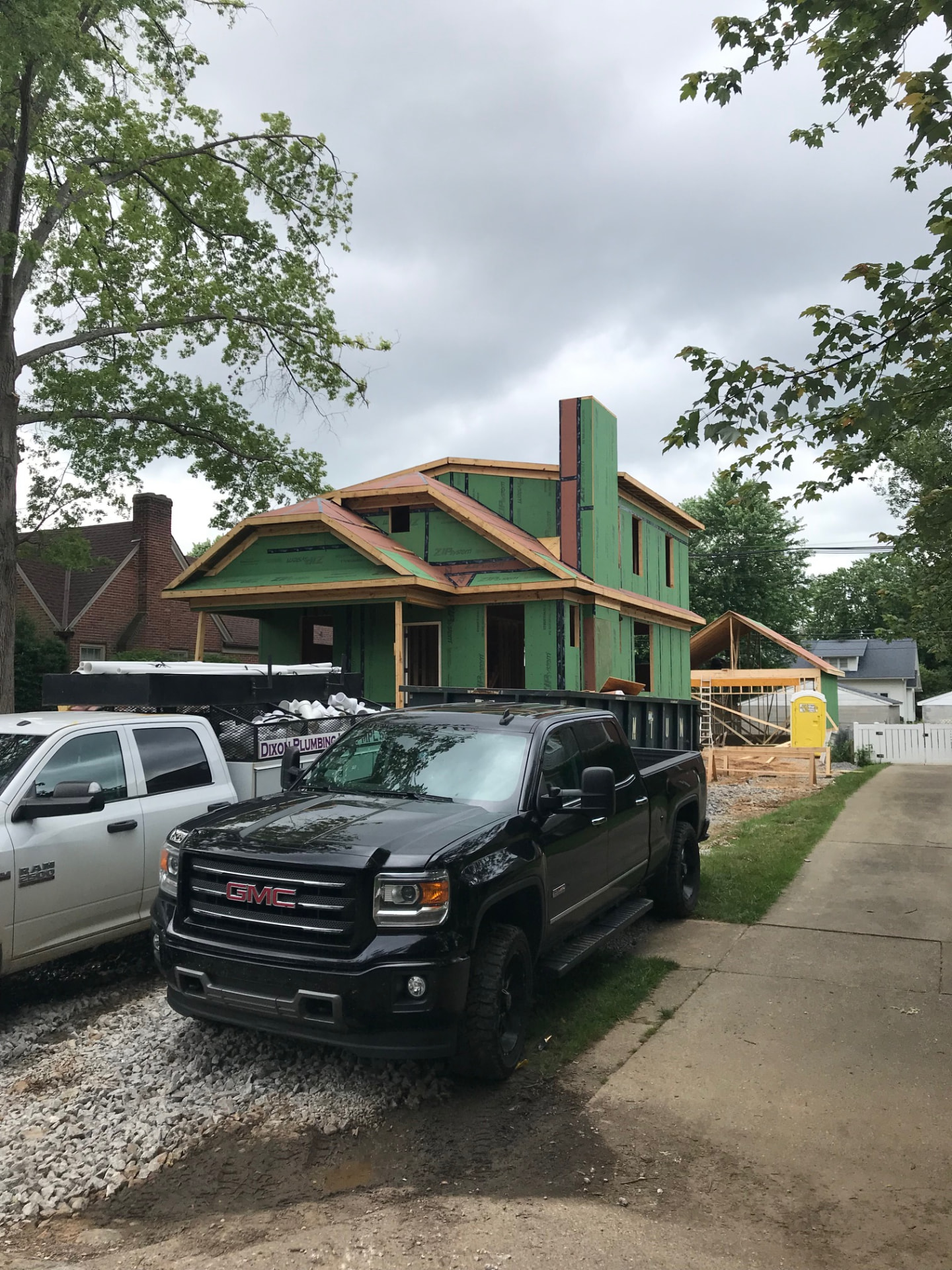 Two-story custom home under construction with framed gables and green ZIP System sheathing