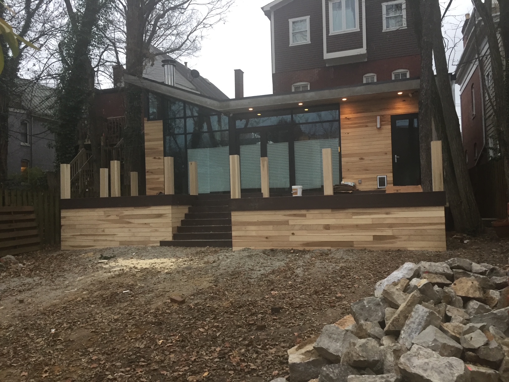 Modern rear addition with floor-to-ceiling glass, cedar siding and a dark standing-seam roof