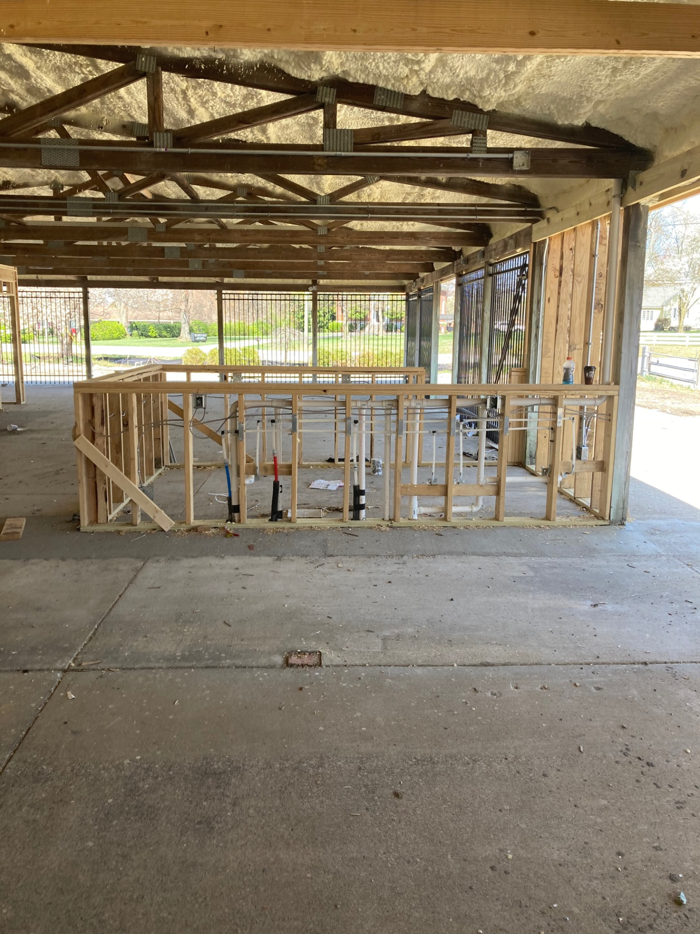 Interior of a post-frame structure with timber trusses, spray foam insulation and new stud framing